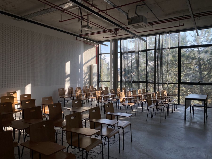 güneş alan boş bir derslik, ahşap sıralar